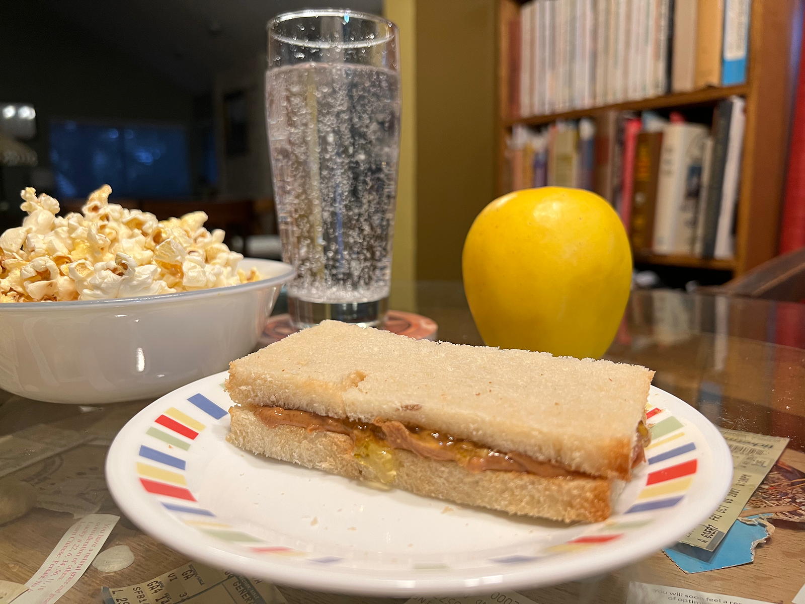 PB&J dinner: A peanut butter and jelly sandwich, popcorn, and an apple for a nutritious light dinner.; sandwiches; popcorn; apples; peanut butter; jelly; jam, marmalade