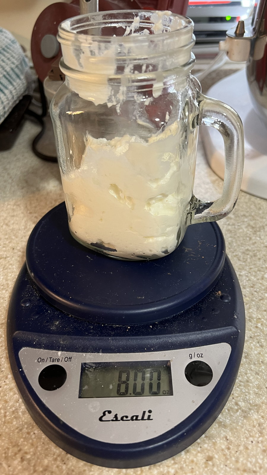 Weighing yogurt for lassi: Weighing one cup of Greek yogurt in a blender-compatible jar for lassi.; yogurt; scale
