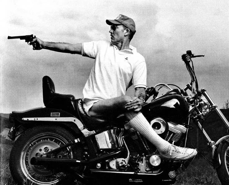 Hunter Thompson motorcycle: Hunter S. Thompson on a motorcycle firing a handgun.; Hunter S. Thompson