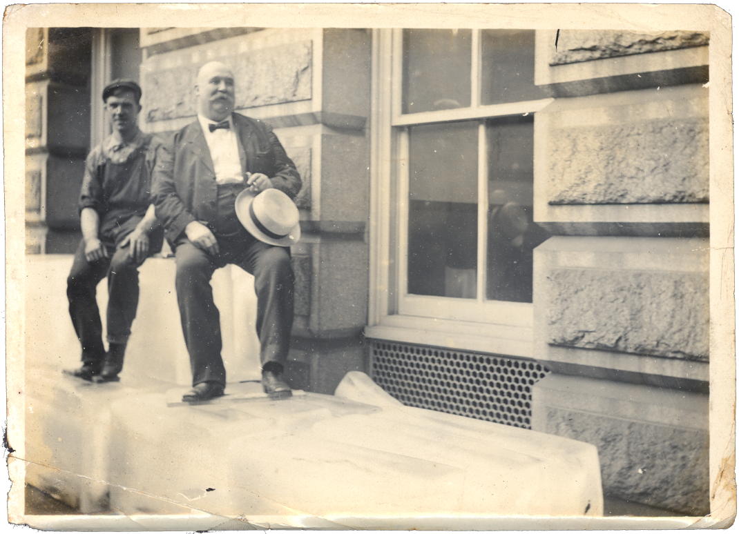 Sitting on ice: “Two men sitting on blocks of ice outside of a building.”; ice